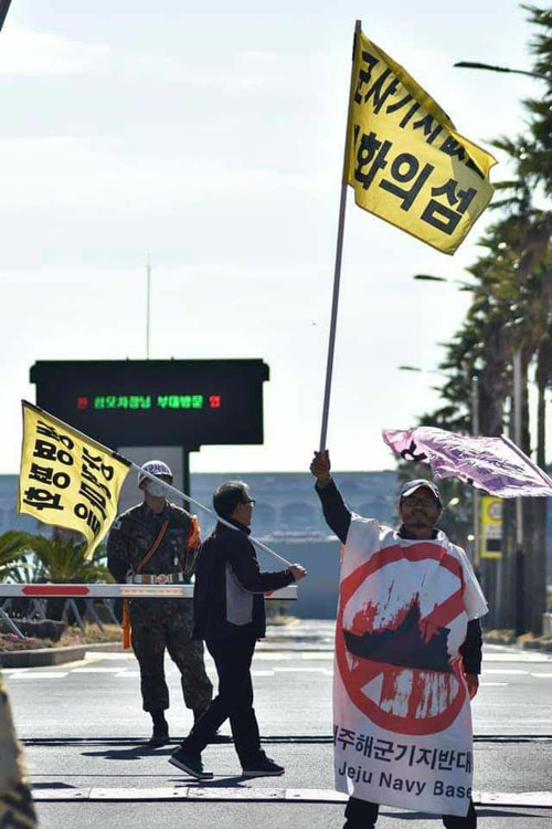 송강호 박사가 해군기지 앞에서 깃발을 들고 있다. 사진 제공 강정평화네트워크